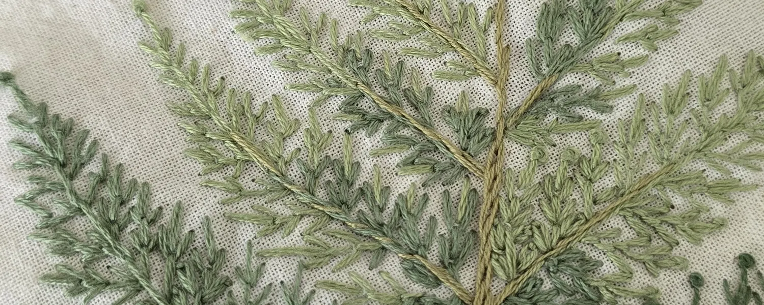 Hand-embroidered fern fronds on natural fabric